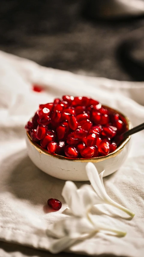 white cloth and red pomegranate in white bowl on table