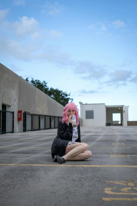 a woman with pink hair is sitting on the ground outside
