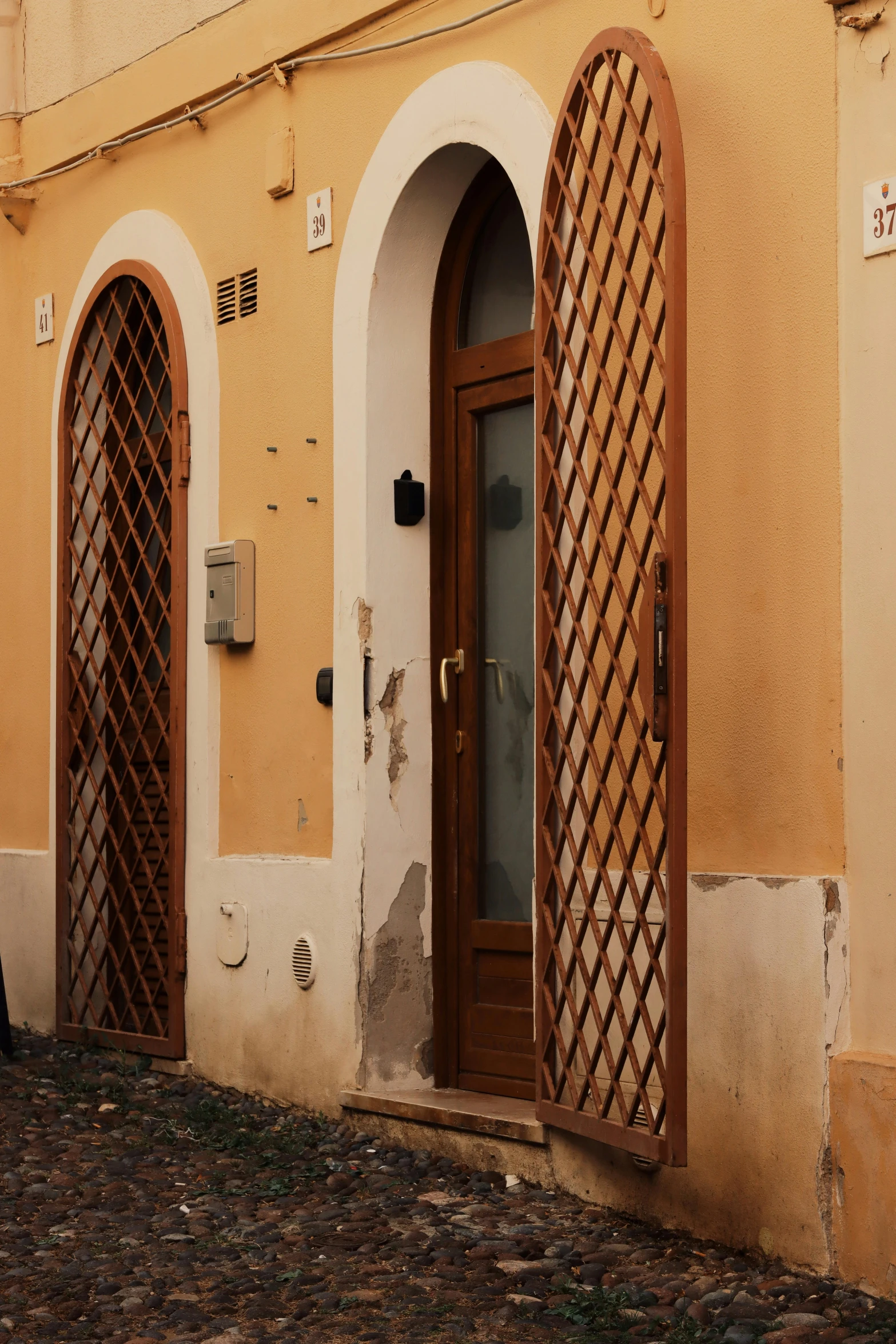 an arched wooden door sitting next to a tall building