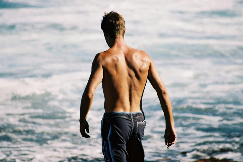 a man in swim trunks on the shore walking