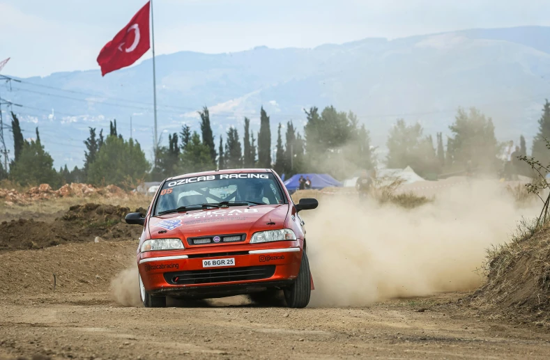 a red car moving around a corner on a dirt road