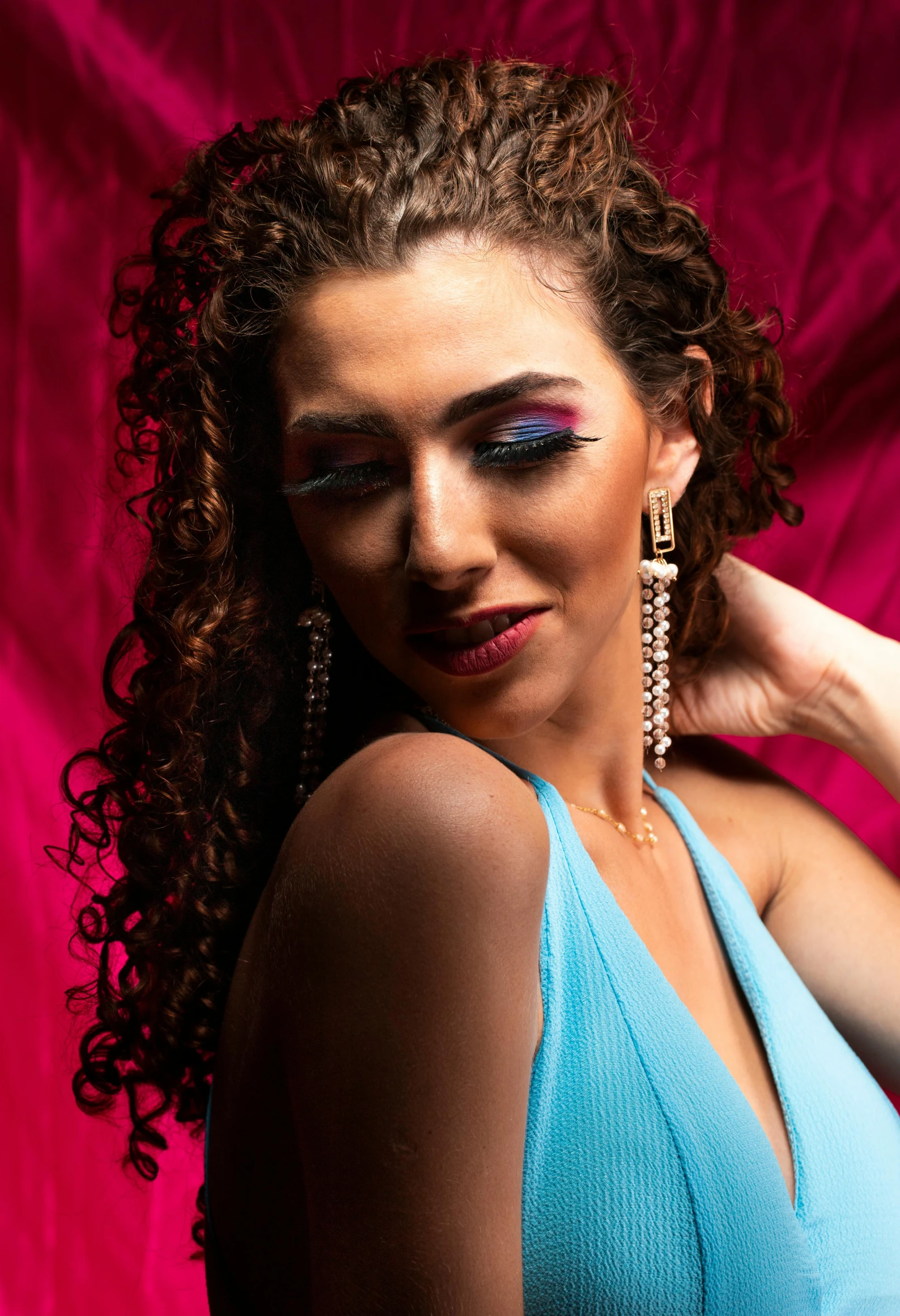 a woman with red makeup and blue top with long curly hair