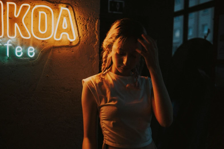 a woman stands by a neon sign at night