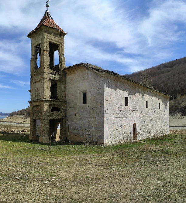 a building with the steeple of a tower in front of mountains