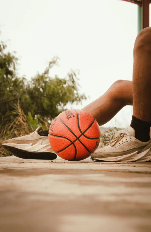 a person sitting on a wooden floor holding a basketball