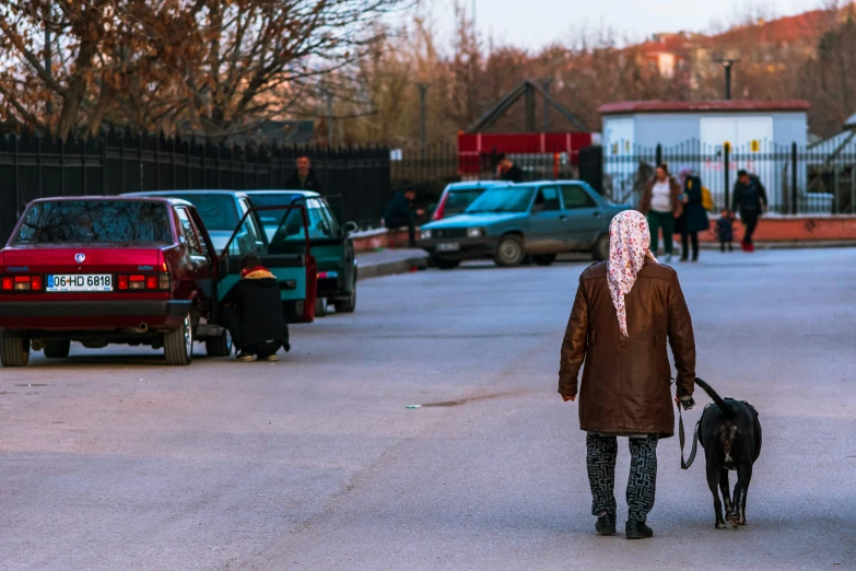 a man with a scarf on walking his dog