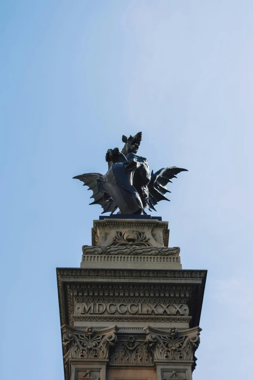 the statue is atop a building with wings