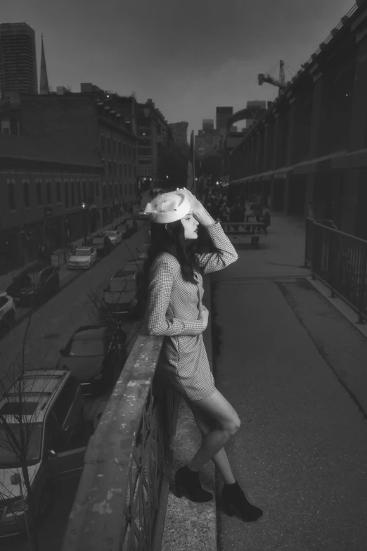 black and white po of woman wearing hat sitting on street