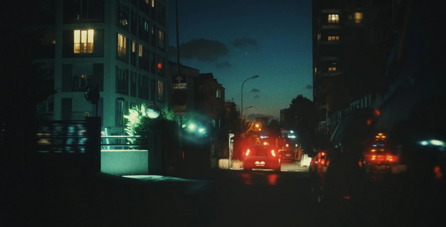 a night scene showing traffic coming around the corner of a city street