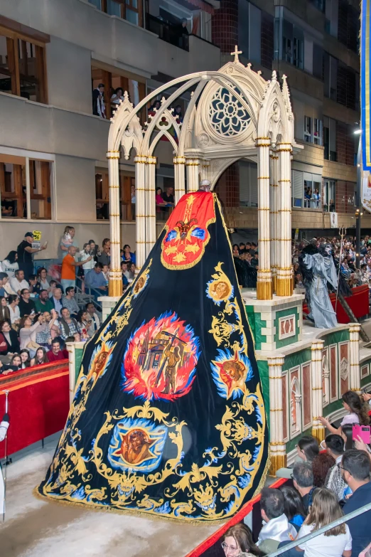 people sitting in a crowd watching a large tapestry