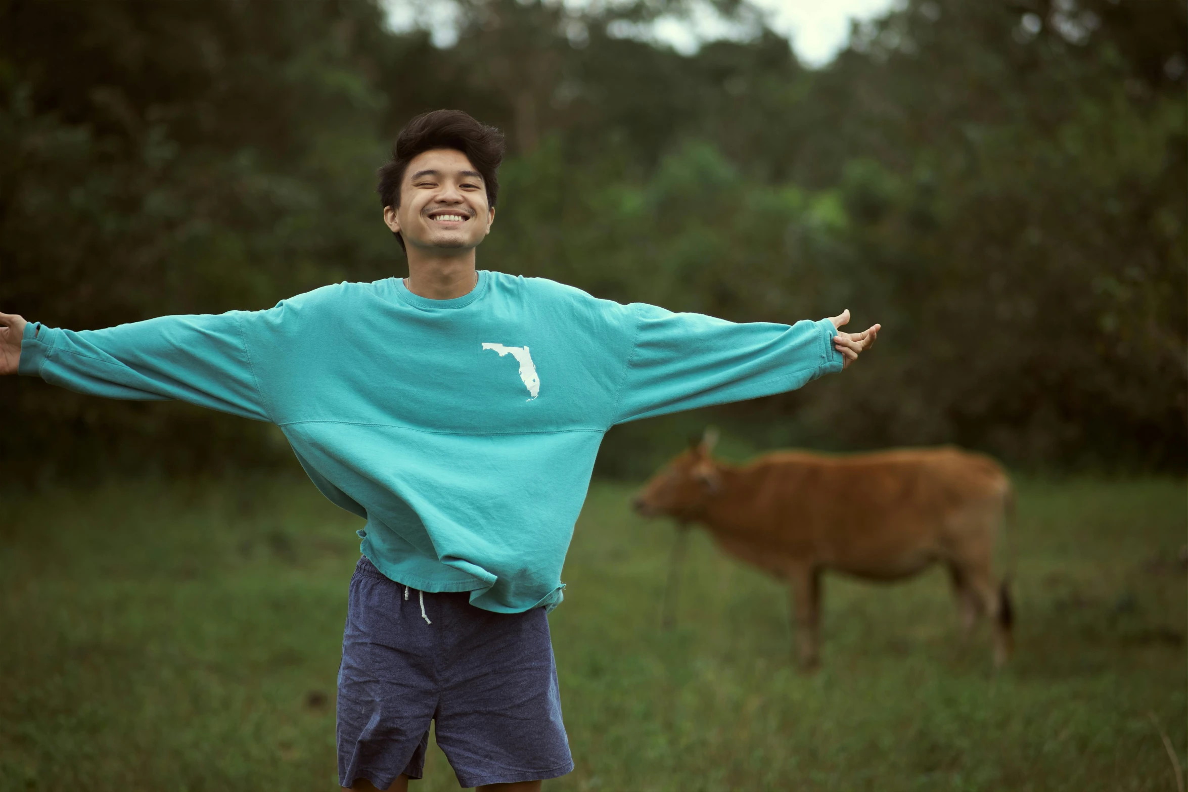 a person in the grass with a cow in the background