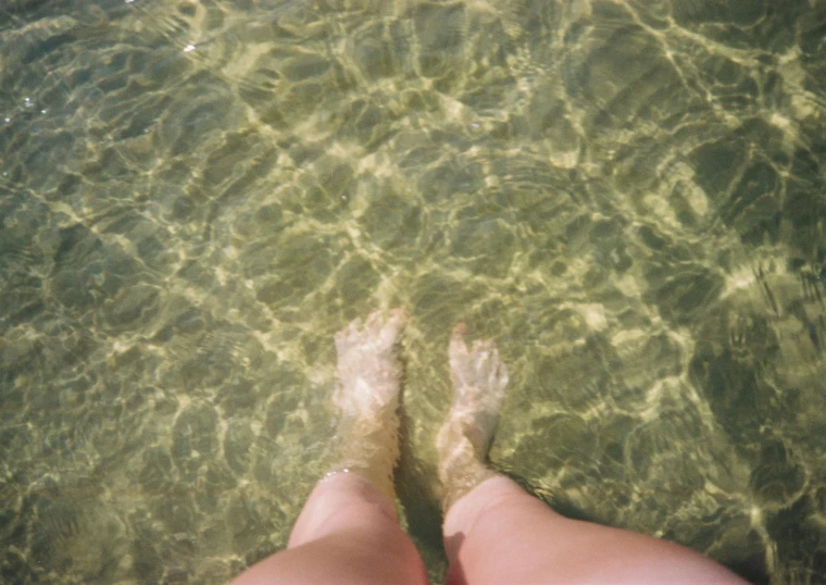 person standing in water looking at the ocean