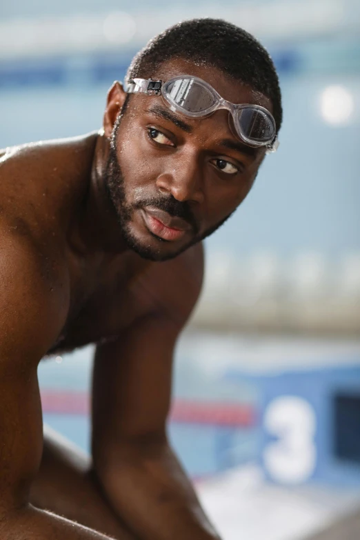 a man squatting on top of a swimming pool wearing goggles