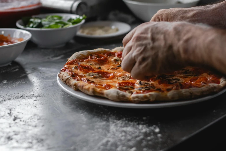 a person reaching for some topping on a pizza