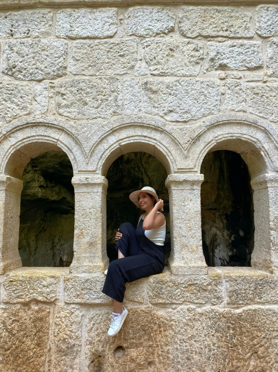 a girl is sitting on the ledge of a building