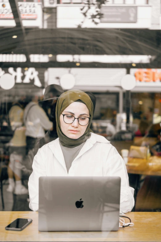 woman in white coat sitting at table with laptop computer