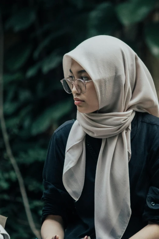 a woman in glasses wearing a hijab and holding a cell phone