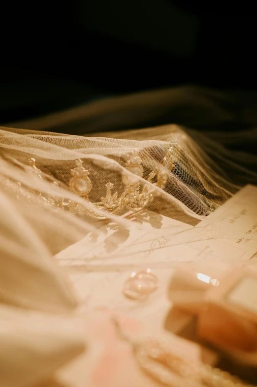 a wedding ring lies on the lace of a wedding gown