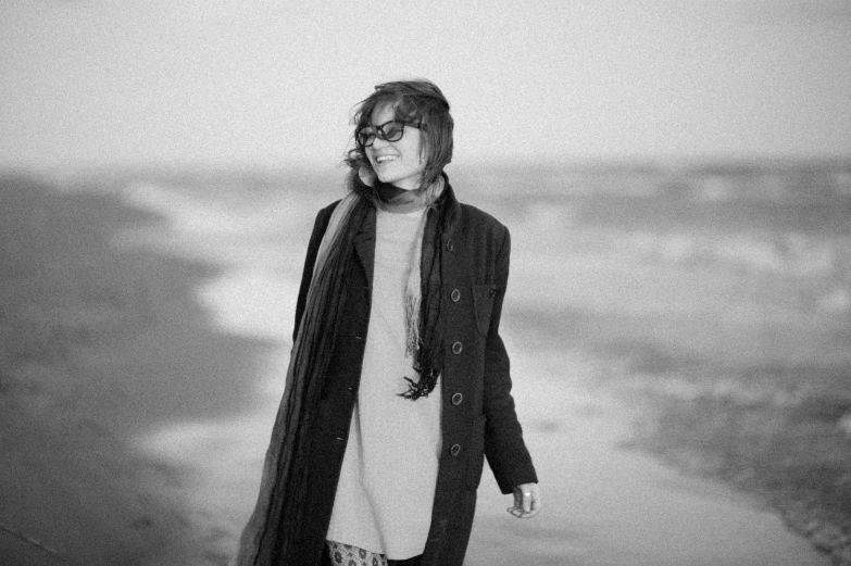 a woman walking next to the ocean looking back