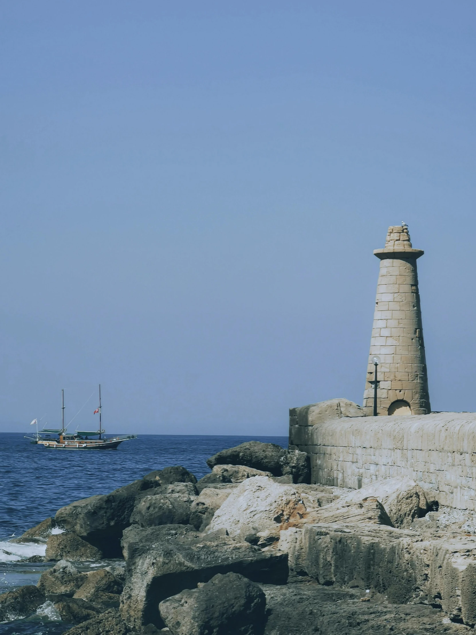 a small light house sits on the coast with the ocean in the background