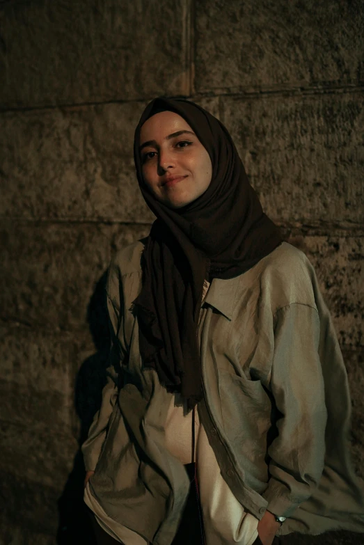 a woman wearing a headscarf standing in front of a stone wall