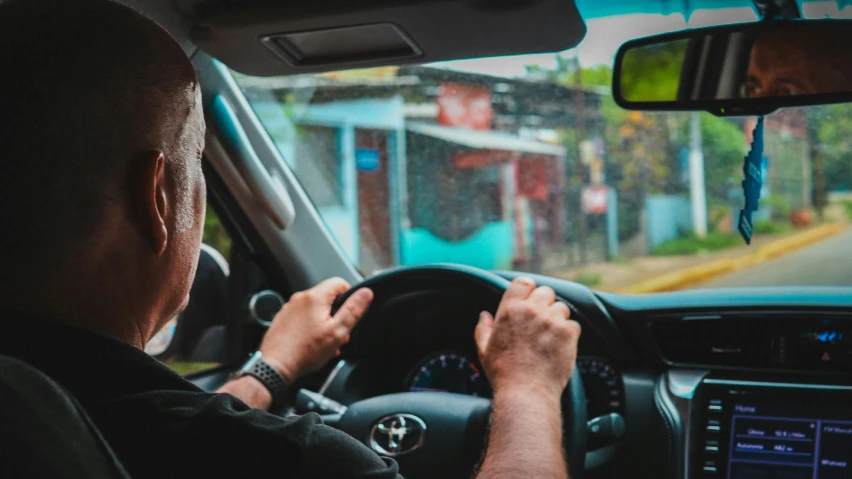 a man that is driving a car down the street