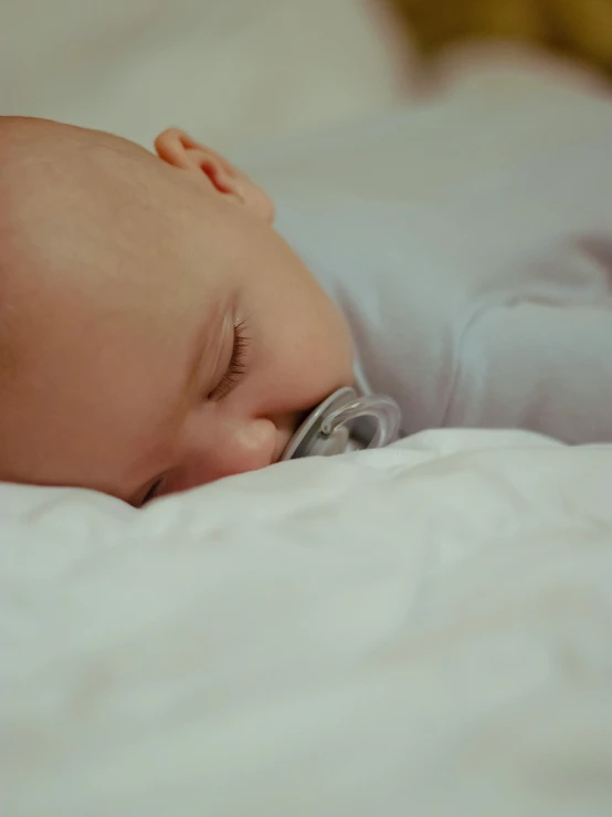 a baby sleeping with a pacifier in its mouth