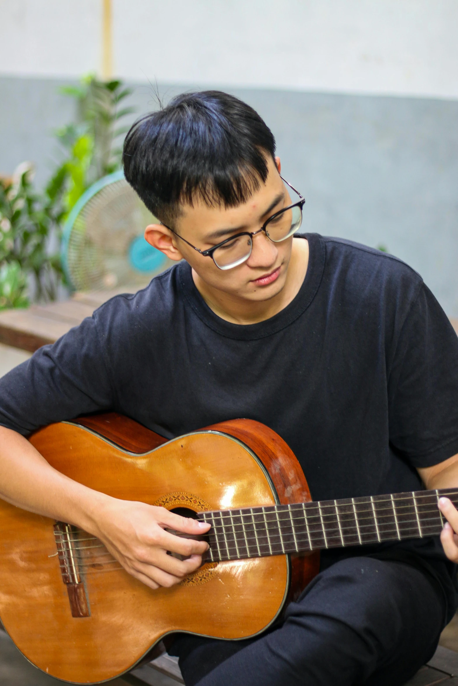 a young man sitting down while playing an acoustic guitar