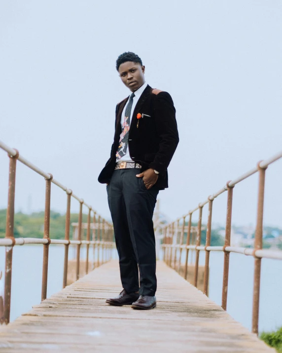 a man in suit and tie stands on wooden dock