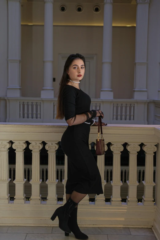 a woman poses on the balcony of a large building