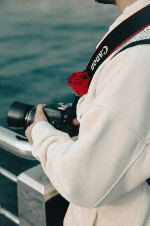 person wearing white coat taking pictures by the water