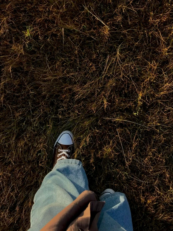 a persons feet standing in a field with grass