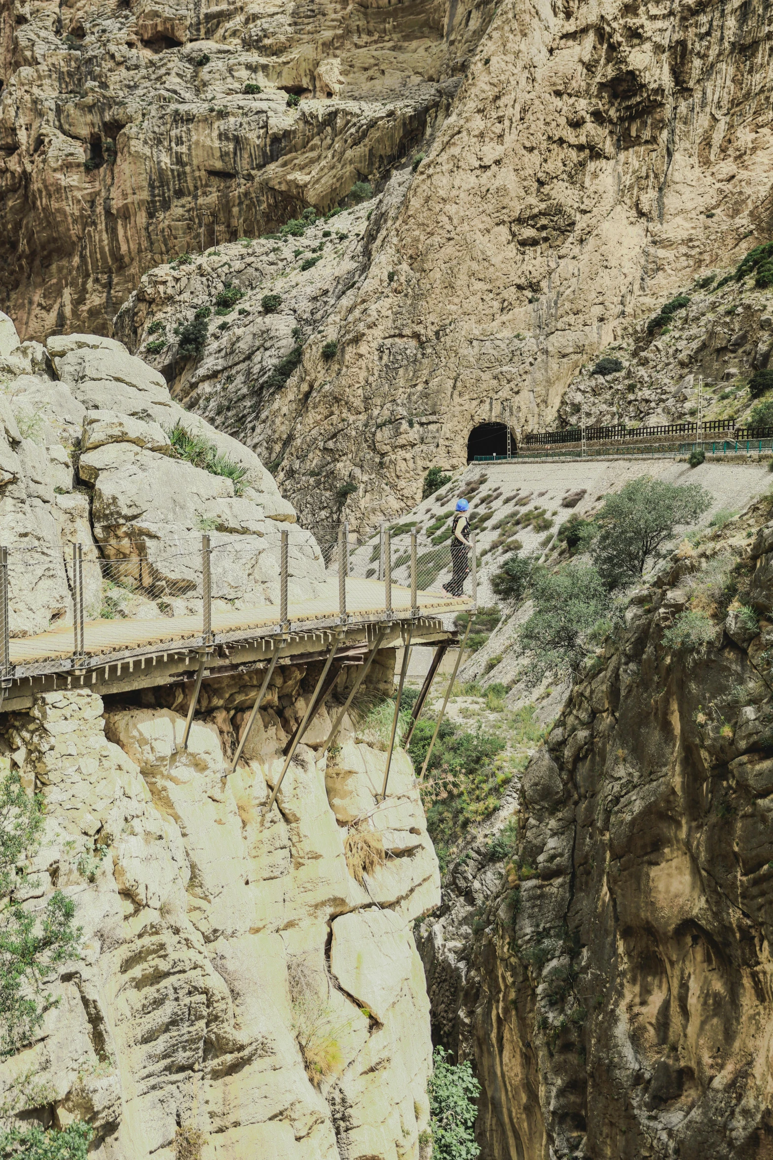 a person riding a bike across a stone bridge on a steep mountain