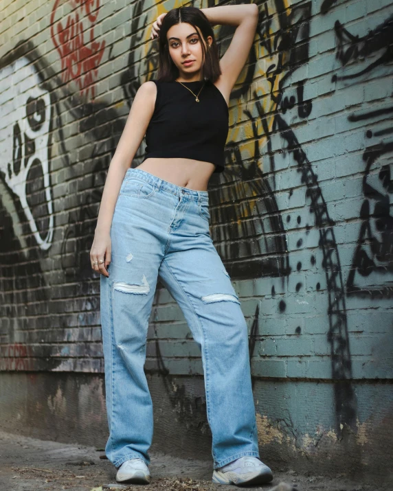 a woman leaning up against a wall with graffiti on it