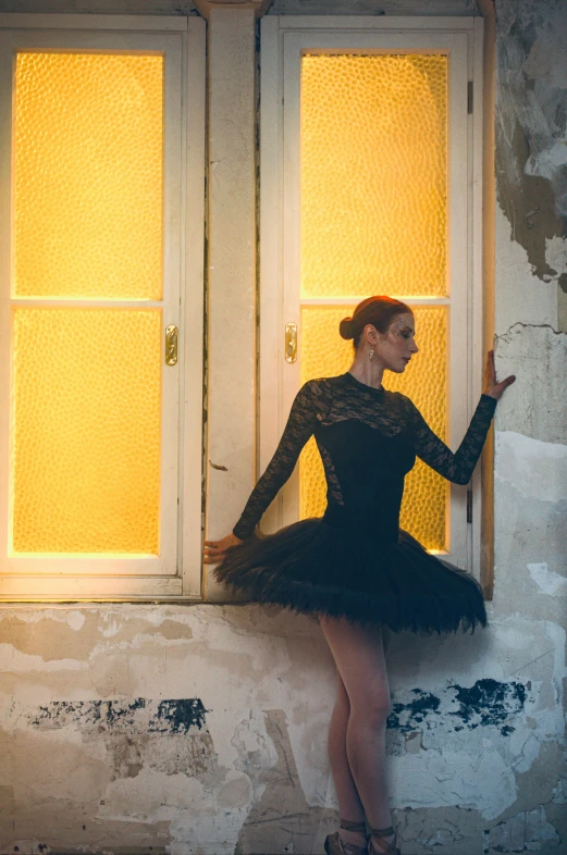 young ballerina posing against the window on an abandoned building