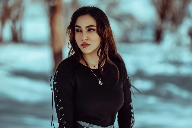 a beautiful young lady wearing all black in front of a snowy scene