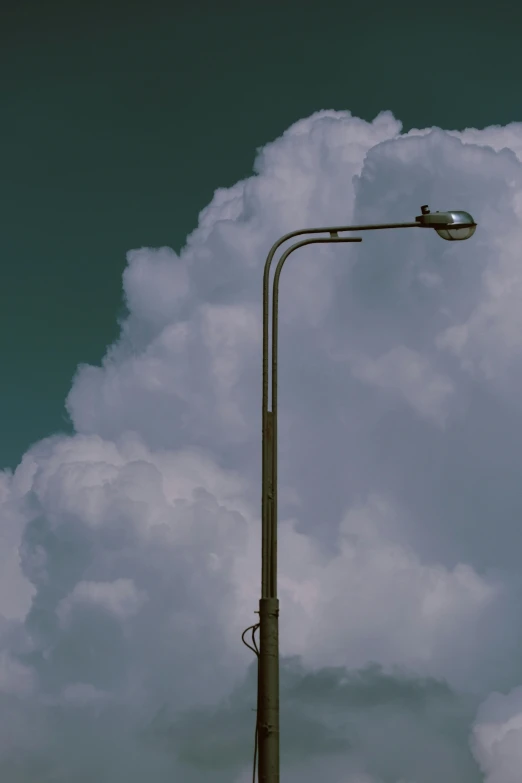 a lamp post with some big fluffy clouds behind it