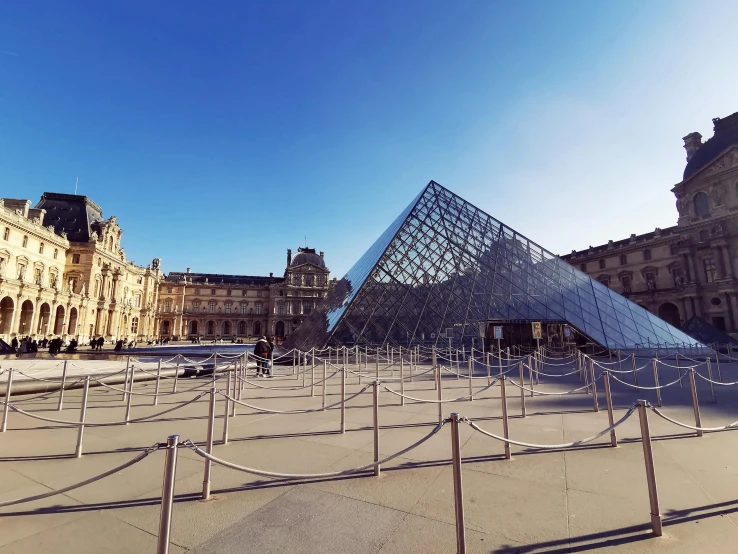 a pyramid statue on the ground in front of large buildings