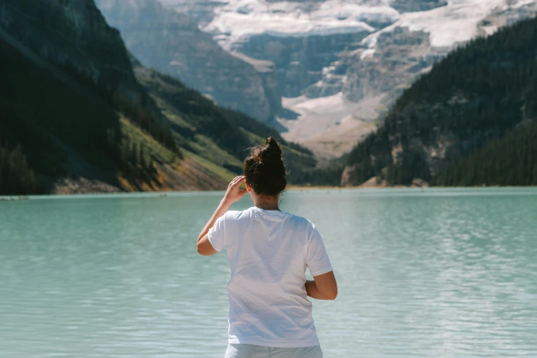 a man standing on the shore of a mountain lake looking at the mountains