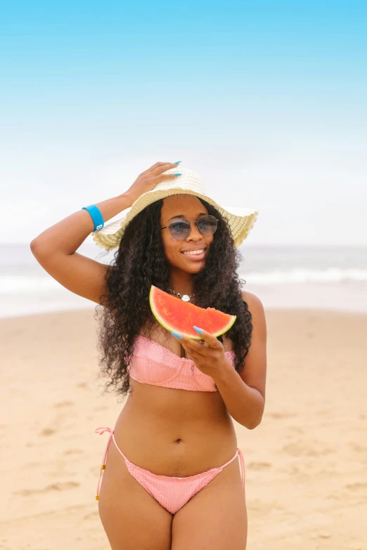 a woman in a bikini holds up a slice of watermelon