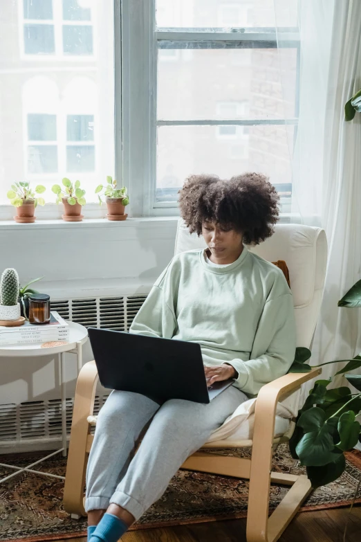 a woman in a light green shirt is using a laptop