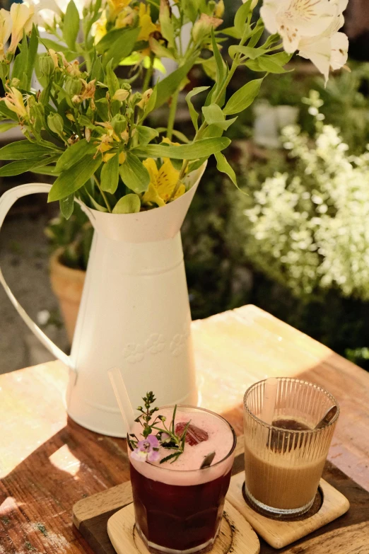 a pitcher of flowers and glasses on a plate