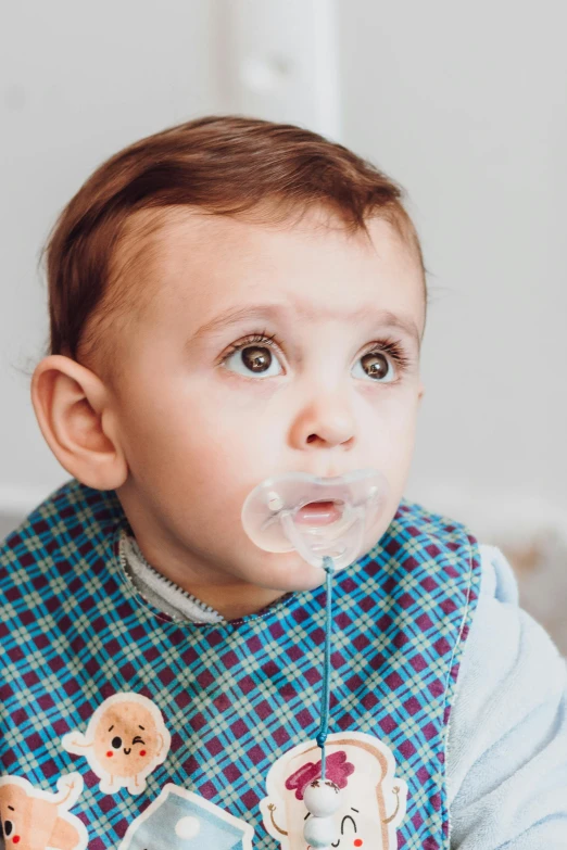 a baby with its tongue out and an object hanging from it's mouth