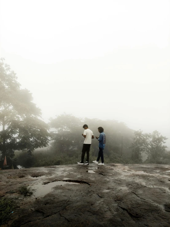 two men standing in the rain with a kite