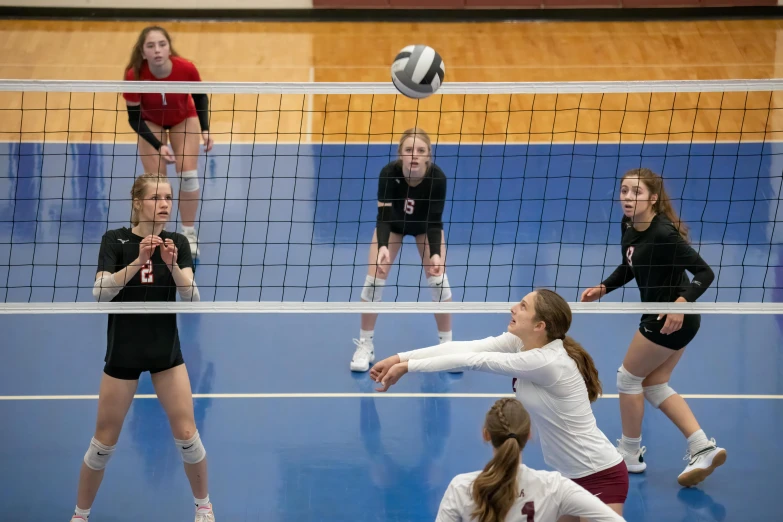 the girls are competing for control of the volleyball ball