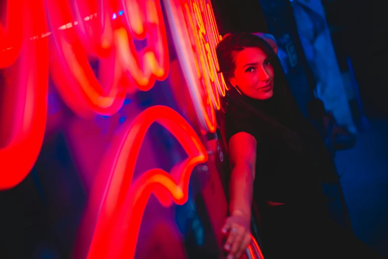 a woman leaning against the neon wall