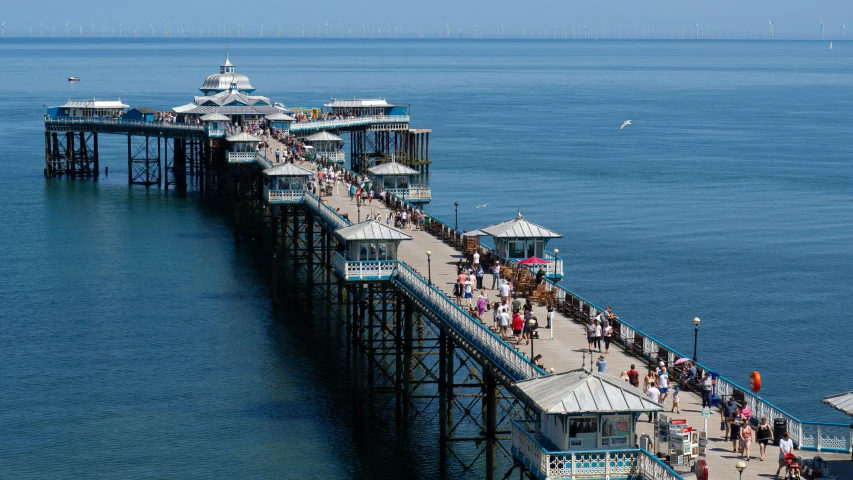 people are walking along the pier at the ocean