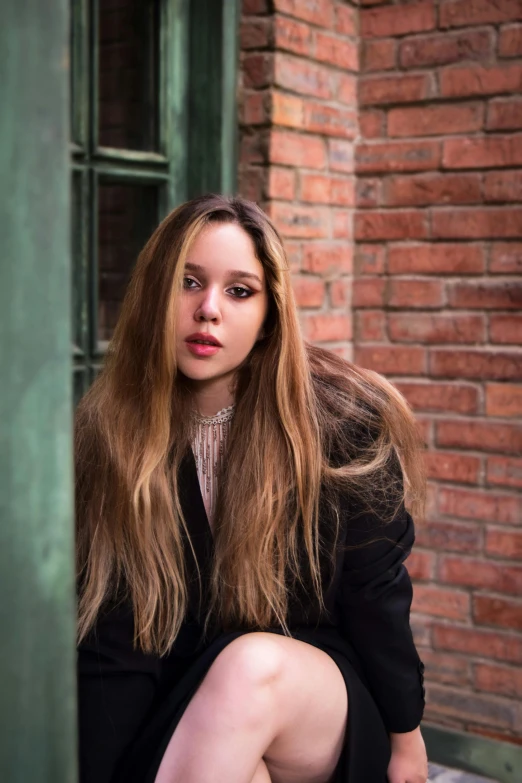 a woman sitting outside of a building wearing a blazer