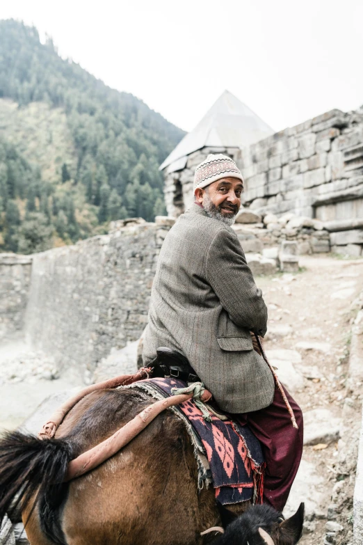 man with a gray robe on riding a horse in the ruins