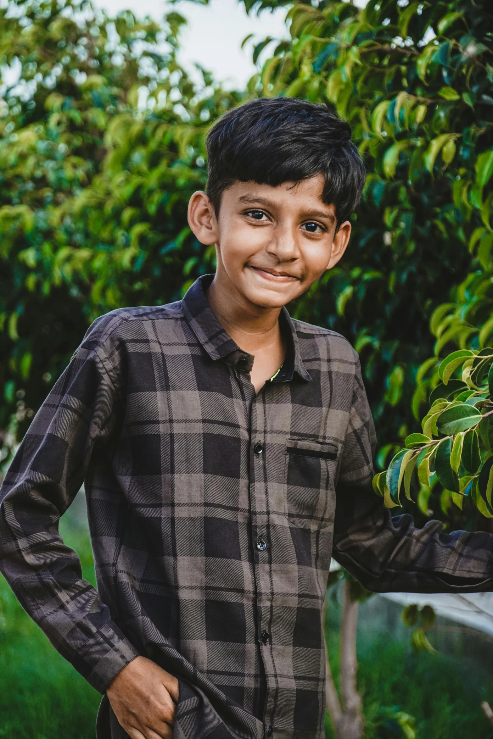 a boy smiles in a field with trees